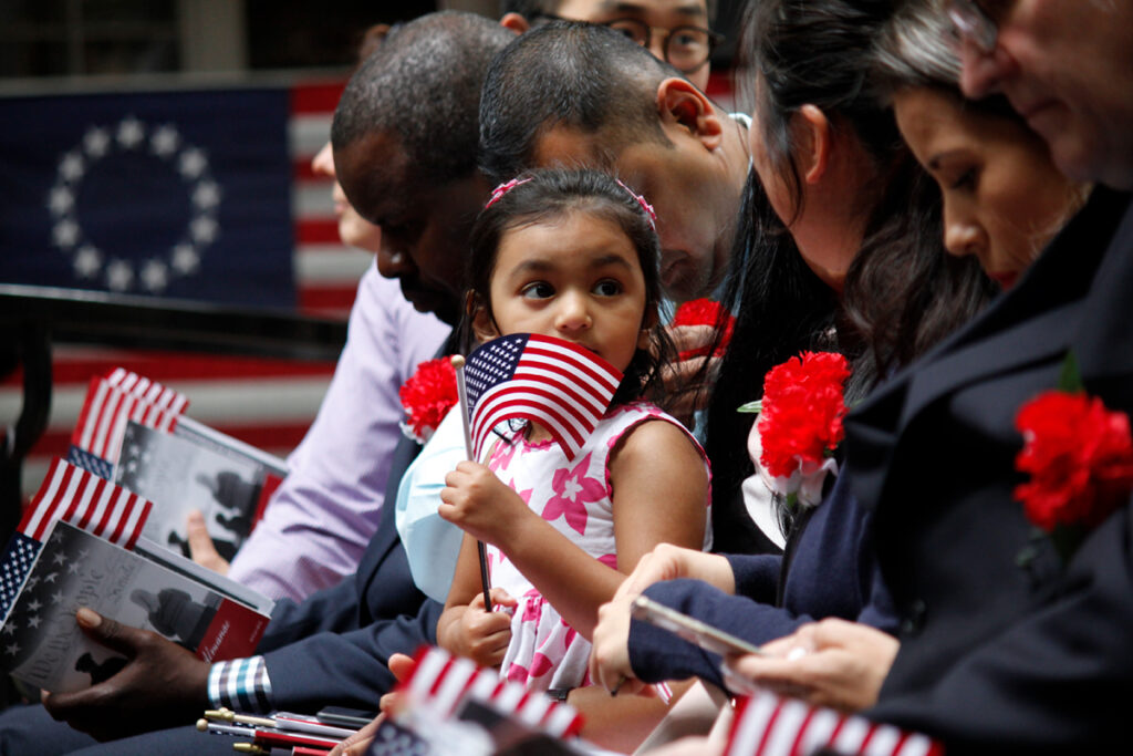 A girl holding an American flag at a citizenship ceremony